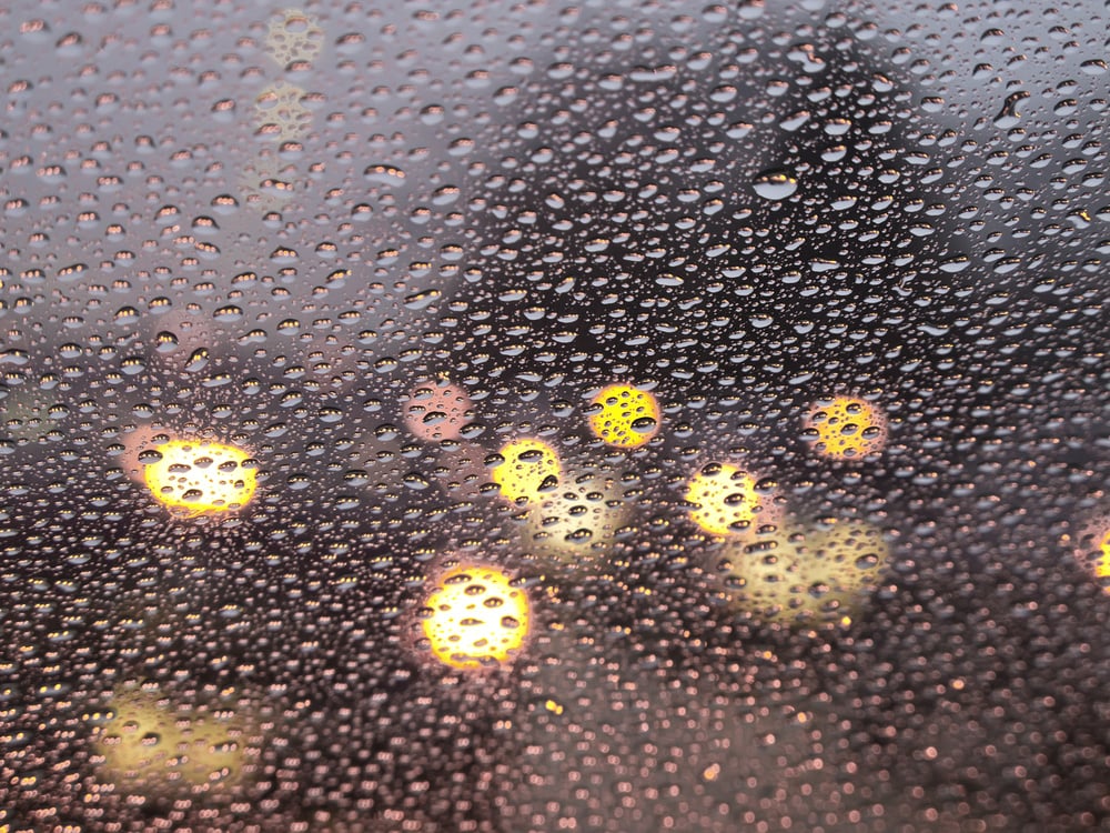 Abstract of rain at rush hour Raindrops all over windshield (selective focus)